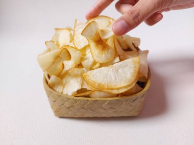 Keripik singkong goreng veya kızarmış cassava cipsi. Geleneksel Endonezya atıştırmalığı. Lezzetli bir tat. Bambu dokuma desenli seramik üzerinde servis edilir. izole edilmiş arka plan beyaz. kopyalama alanı.