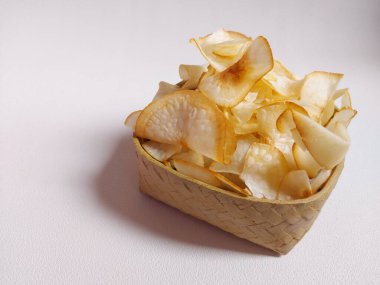 Keripik singkong goreng veya kızarmış cassava cipsi. Geleneksel Endonezya atıştırmalığı. Lezzetli bir tat. Bambu dokuma desenli seramik üzerinde servis edilir. izole edilmiş arka plan beyaz. kopyalama alanı.