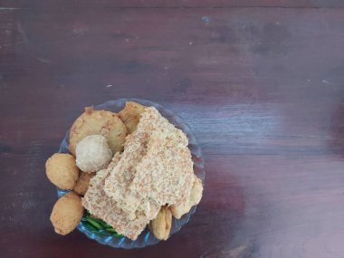 Çeşitli kızarmış atıştırmalıklar. Endonezya atıştırmalıkları. Kızarmış tempeh, combro, kızarmış tofu ve bakwandan oluşuyor. Çiğ yeşil biberli. Lezzetli ve lezzetli. Tabakta servis edilir..