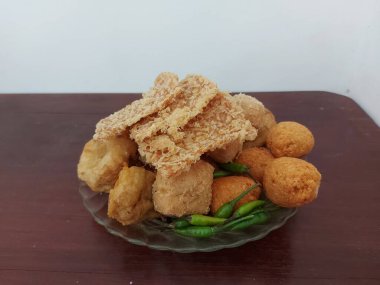 Çeşitli kızarmış atıştırmalıklar. Endonezya atıştırmalıkları. Kızarmış tempeh, combro, kızarmış tofu ve bakwandan oluşuyor. Çiğ yeşil biberli. Lezzetli ve lezzetli. Tabakta servis edilir..