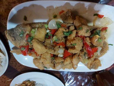 Ikan gurame goreng veya kızarmış sazan. Beyaz tabakta servis ediliyor. Endonezya geleneksel yemekleri. Lezzetli.