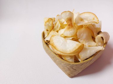 Keripik singkong goreng veya kızarmış cassava cipsi. Geleneksel Endonezya atıştırmalığı. Lezzetli bir tat. Bambu dokuma desenli seramik üzerinde servis edilir. izole edilmiş arka plan beyaz. kopyalama alanı.
