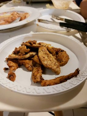 Beyaz plastik tabakta servis edilen ızgara tavuk..