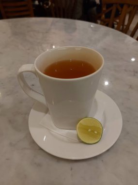 Sıcak yeşil limon çayı. Beyaz porselen kupada servis edildi. Tatlı ve ekşi tat.