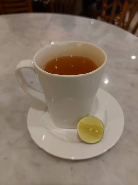 Sıcak yeşil limon çayı. Beyaz porselen kupada servis edildi. Tatlı ve ekşi tat.