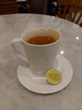 Sıcak yeşil limon çayı. Beyaz porselen kupada servis edildi. Tatlı ve ekşi tat.
