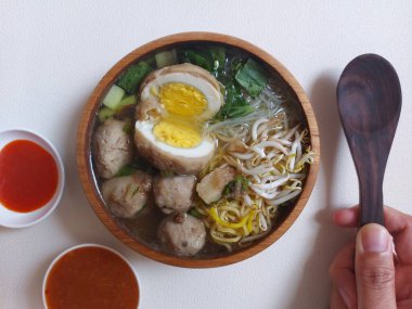 Yumurtalı köfte. Hardal yeşillikleri, lahanalar, sarı erişteler ve ses ile tamamlanmış. Tahta kaselerde servis edilir. Lezzetli bir tat. izole edilmiş arkaplan.