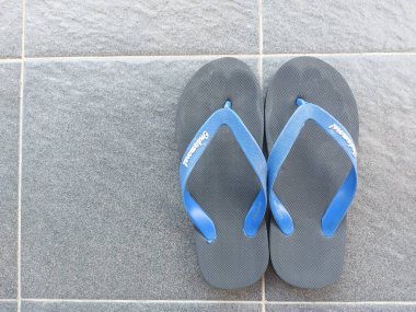 Bandung,Indonesia-July 8 2022: black rubber sandal with blue strap on grey floor. indomaret brand. 