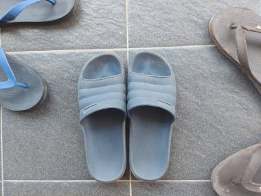 Gri zeminde mavi lastik sandaletler. Kirli ve tozlu