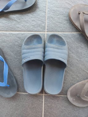 Gri zeminde mavi lastik sandaletler. Kirli ve tozlu