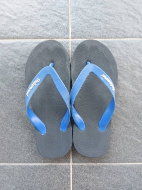 Bandung, Endonezya-8 Temmuz 2022: gri zemin üzerinde mavi kayışlı siyah lastik sandalet. indomaret markası. 