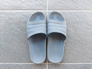 Gri zeminde mavi lastik sandaletler. Kirli ve tozlu