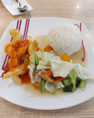 Yemek ayarla. Tatlı ve ekşi balık fileto pilavı ve beyaz tabakta servis edilen kızarmış sebzeler. Lezzetli bir tat. Endonezya 'da geleneksel Çin yemekleri.