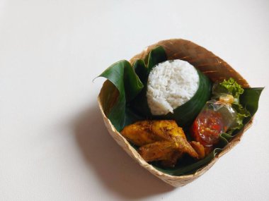 Endonezya geleneksel set yemeği. Bambu dokuma kutusunda muz yaprağında servis ediliyor. Pirinç, kızarmış tavuk, acı biber ve maruldan oluşur. Lezzetli