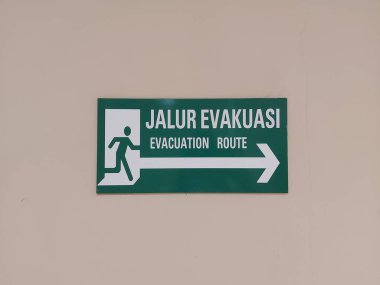 Tahliye güzergahı tabelası duvarda. İngilizce ve Endonezya metinleriyle. izole arkaplan