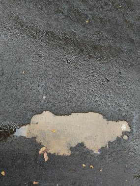 Asfalt yol hasar görmüş ve beton kaldırımın içi görünür durumda.