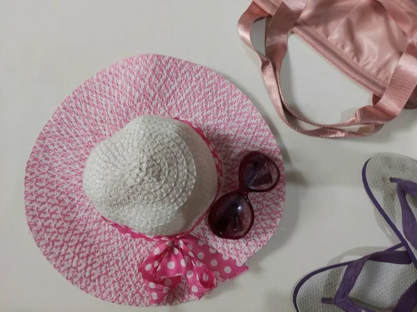 summer vibe concept. equipped with pink beach hat, glasses, bag and rubber sandals. isolated background in white. top view.