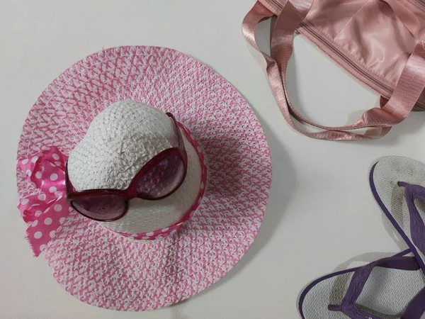 summer vibe concept. equipped with pink beach hat, glasses, bag and rubber sandals. isolated background in white. top view.
