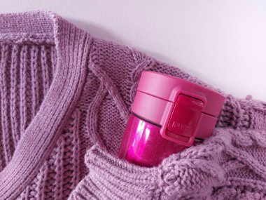 Mor örgü süveter ve pembe sıcak su bardak. Kış titreşimleri. izole edilmiş arkaplan