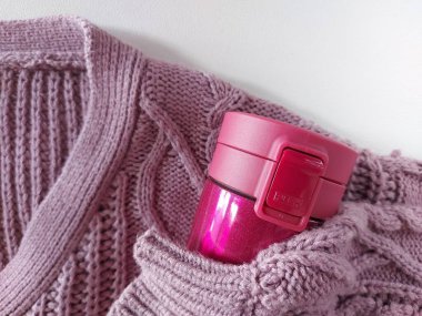 Mor örgü süveter ve pembe sıcak su bardak. Kış titreşimleri. izole edilmiş arkaplan
