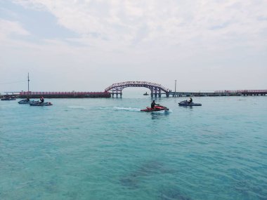 jakarta, Endonezya-Temmuz 24 2022: jembatan cinta. Endonezya 'nın başkenti Jakarta' daki en ünlü köprüdür. Parlak bir günde, güzel mavi denizde jet ski seven insanlarla..