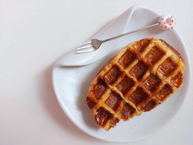Beyaz tabakta Croffle ya da kruvasan waffle. Viral tatlı ya da atıştırmalık. Zevkli. Genellikle herhangi bir malzemeyle servis edilir. Lezzetli. İçi kıtır kıtır. Beyazlar içinde izole edilmiş bir arka plan. Boşluğu kopyala.  