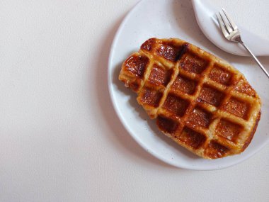 Beyaz tabakta Croffle ya da kruvasan waffle. Viral tatlı ya da atıştırmalık. Zevkli. Genellikle herhangi bir malzemeyle servis edilir. Lezzetli. İçi kıtır kıtır. Beyazlar içinde izole edilmiş bir arka plan. Boşluğu kopyala.  
