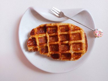 Beyaz tabakta Croffle ya da kruvasan waffle. Viral tatlı ya da atıştırmalık. Zevkli. Genellikle herhangi bir malzemeyle servis edilir. Lezzetli. İçi kıtır kıtır. Beyazlar içinde izole edilmiş bir arka plan. Boşluğu kopyala.  