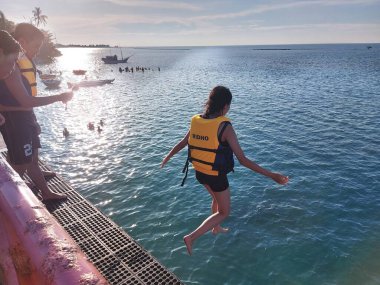 jakarta,indonesia-july 23 2022:famous spot where tourists jump from 'jembatan cinta' or the bridge to the sea on the island of tidung, jakarta, indonesia