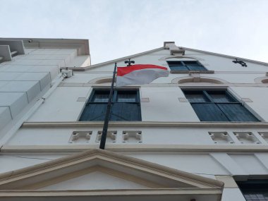 Tahta pencerede eski tarz bir bambuya asılı Endonezya bayrağı.