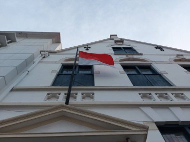 Tahta pencerede eski tarz bir bambuya asılı Endonezya bayrağı.