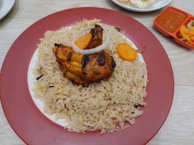 Bir tabak mandhi pilavı tavuğu. Arap Yarımadası 'nın güneyinden başlayıp Endonezya' ya yayılan geleneksel bir yemektir. Patates kızartması, acı biber sosu ve sebze turşusuyla birlikte.