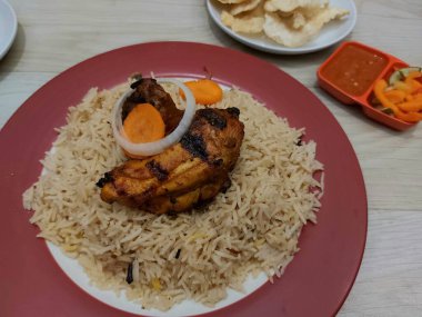 Bir tabak mandhi pilavı tavuğu. Arap Yarımadası 'nın güneyinden başlayıp Endonezya' ya yayılan geleneksel bir yemektir. Patates kızartması, acı biber sosu ve sebze turşusuyla birlikte.