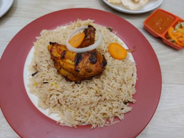 Bir tabak mandhi pilavı tavuğu. Arap Yarımadası 'nın güneyinden başlayıp Endonezya' ya yayılan geleneksel bir yemektir. Patates kızartması, acı biber sosu ve sebze turşusuyla birlikte.