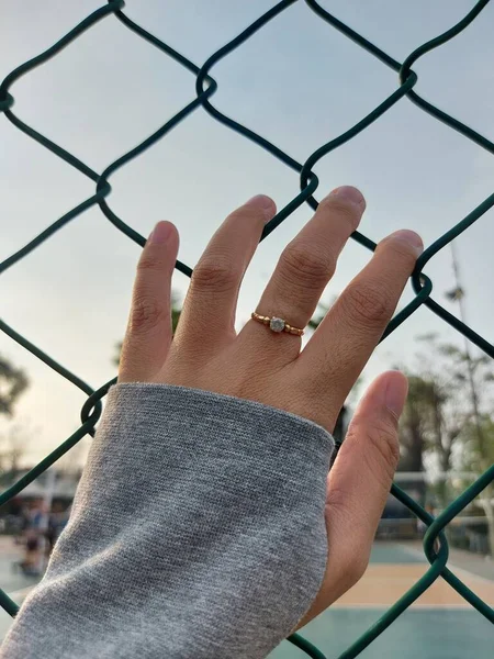 woman\'s hand blocked by wire mesh fence