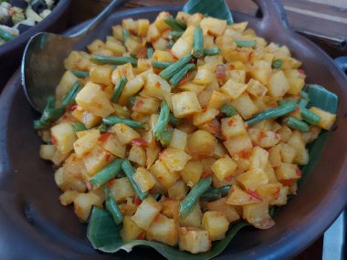 Green bean and potato stir fry. Served on clay plate. Savory taste