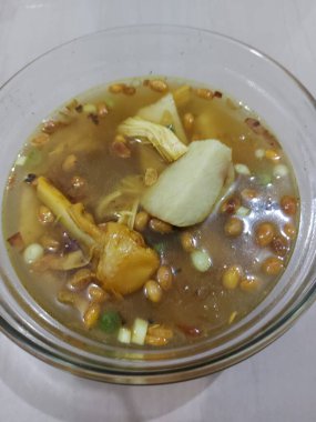 Clear chicken knee soup with rice cake. Consist of rice cake,chicken knee, rice cake,fried peanut and spring onion. Served on a bowl. Savory taste.