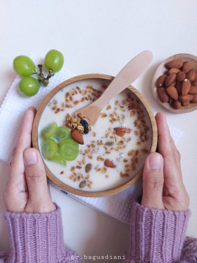 Granola with soya milk, whole almond, green grapes and dried fruit. Served on wooden bowl. Healthy and vegetarian food. Isolated background in white.