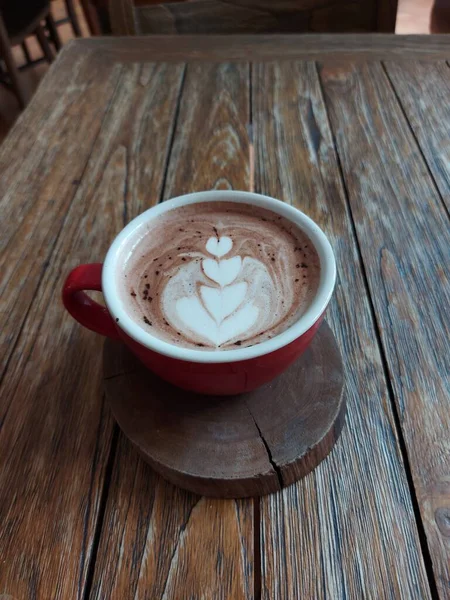 赤磁器のカップにラテアートのコーヒー 木製のテーブルで提供します 甘い味 — ストック写真