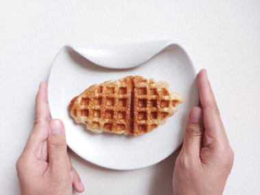 Beyaz tabakta Croffle ya da kruvasan waffle. Viral tatlı ya da atıştırmalık. Zevkli. Genellikle herhangi bir malzemeyle servis edilir. Lezzetli. İçi kıtır kıtır. Beyazlar içinde izole edilmiş bir arka plan. Boşluğu kopyala.