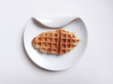 Beyaz tabakta Croffle ya da kruvasan waffle. Viral tatlı ya da atıştırmalık. Zevkli. Genellikle herhangi bir malzemeyle servis edilir. Lezzetli. İçi kıtır kıtır. Beyazlar içinde izole edilmiş bir arka plan. Boşluğu kopyala.