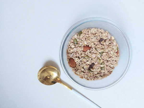 Overnight oat meal with dried fruit and grains on a bowl. Completed with golden spoon. Healthy breakfast. Isolated background in white.