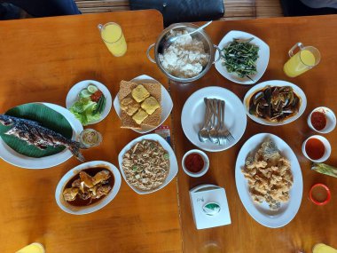 Bogor, Endonezya-17 Ağustos 2022: Endonezya usulü, Endonezya usulü, çeşitli yemeklerin içeriği ile masa durumu. Izgara yayın balığı, kızarmış tofu, lotek, kızarmış lahana, yeşil midye vs..