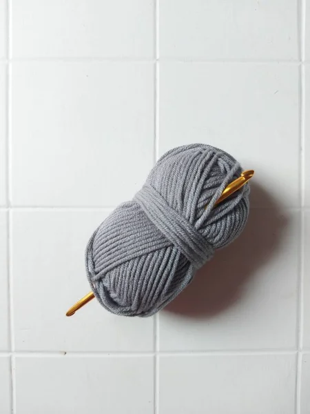 gray knitting thread with gold hook.  isolated background in white