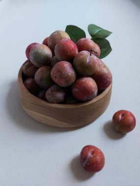 Ahşap kasede erik meyvesi yığını. İzole edilmiş arkaplan