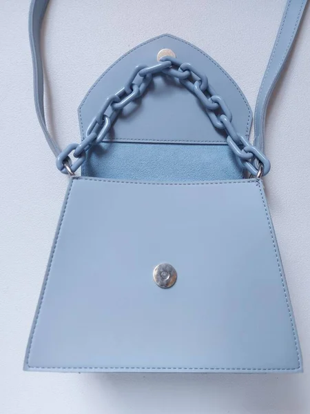 Women sling bag with chain on blue color.  Isolated background in white