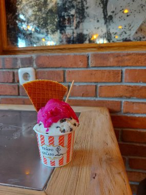 Yogyakarta, Endonezya - Ekim 15 2022: 'tempo dondurma' dan bir fincan dondurma. Ejderha meyvesi ve hindistan cevizli çikolata aromalı. Krep ve kaşıkla tamamlanmış. Jogja şehrinde ünlü ve viral dondurmadır.