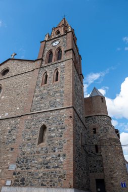 Mavi gökyüzünün arka planında çan kulesi olan bir kilisenin cephesi.