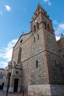 Mavi gökyüzünün arka planında çan kulesi olan bir kilisenin cephesi.