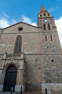 Mavi gökyüzünün arka planında çan kulesi olan bir kilisenin cephesi.